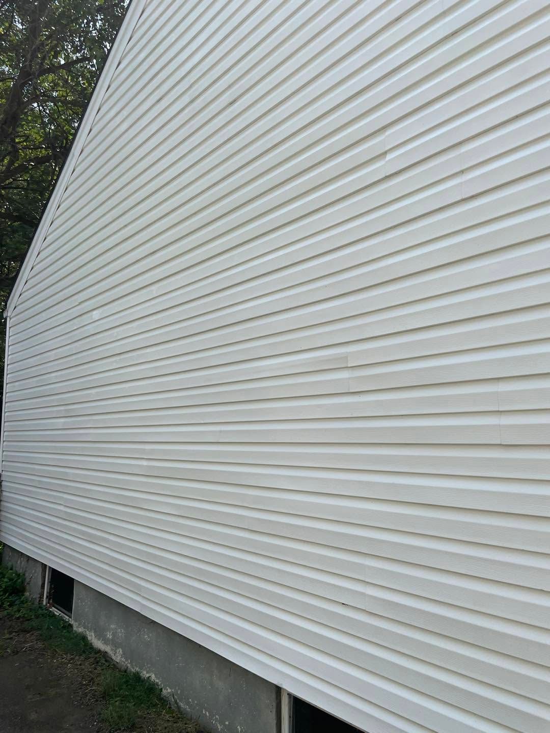White vinyl-sided house exterior with a concrete foundation and narrow strip of grass