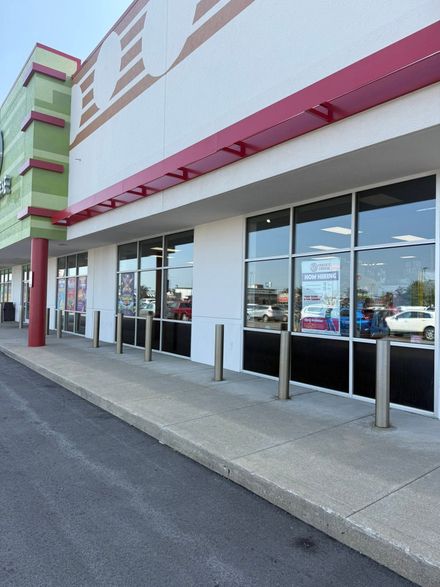 Storefront with glass windows, pink trim, and a sidewalk parking area outside the entrance
