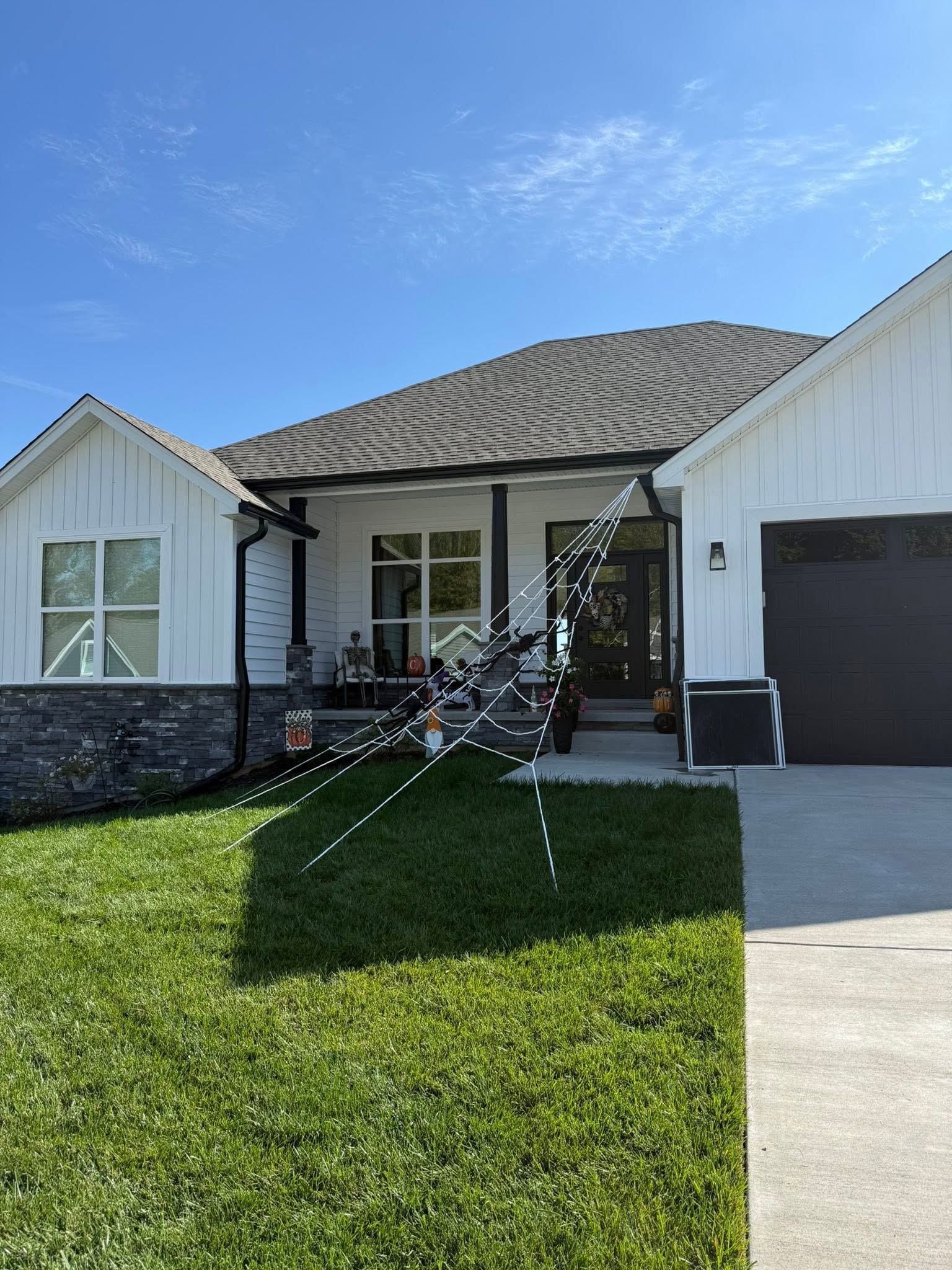 Front view of a white house with a tiled roof, black front door, and green lawn under a blue sky