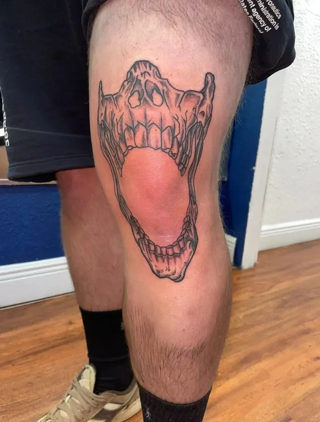 A close-up of a leg with a large open-mouth tattoo on the thigh.