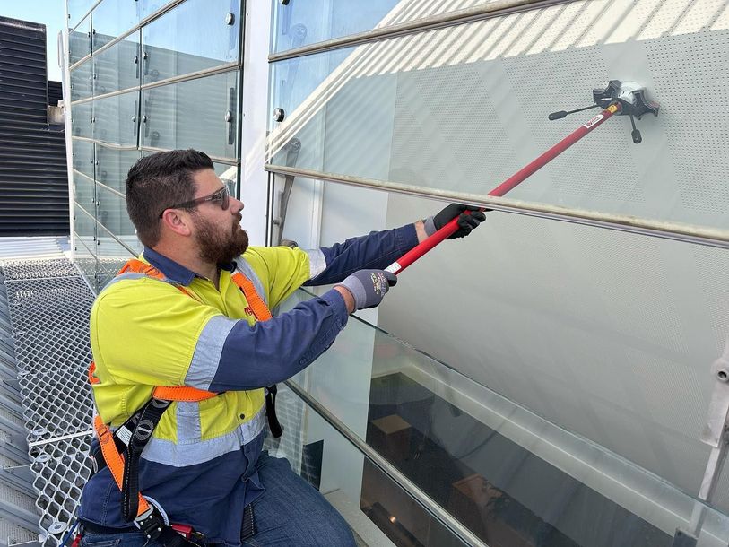 A man is cleaning a building with a long pole. A man is cleaning a building with a long pole.
