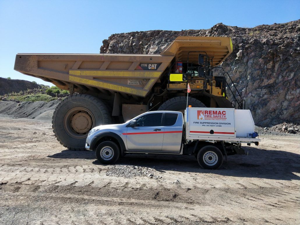 A white truck is parked in front of a large dump truck.