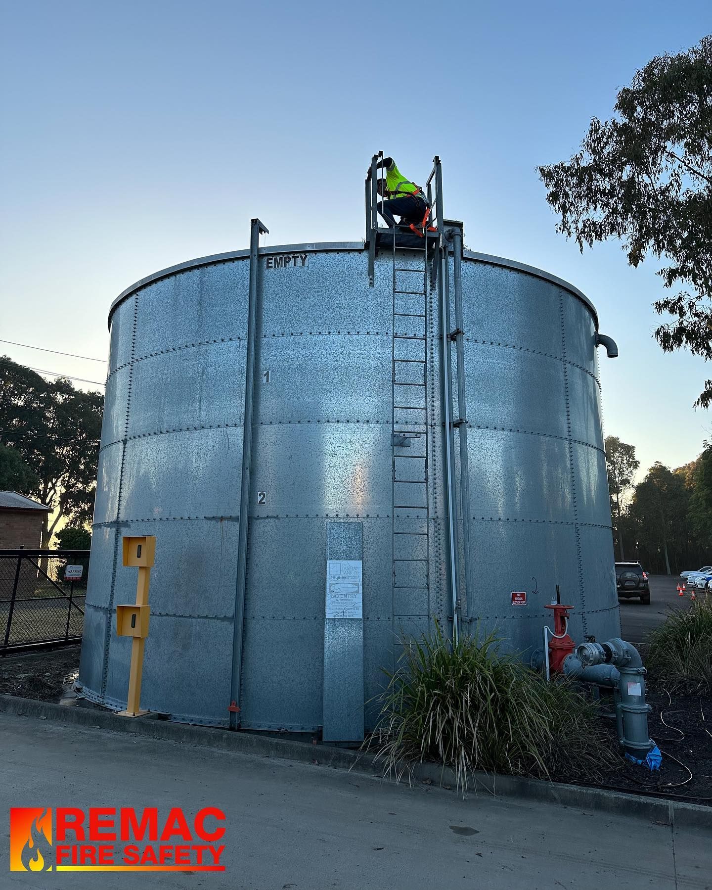 A man is standing on top of a large metal tank A man is standing on top of a large metal tank
