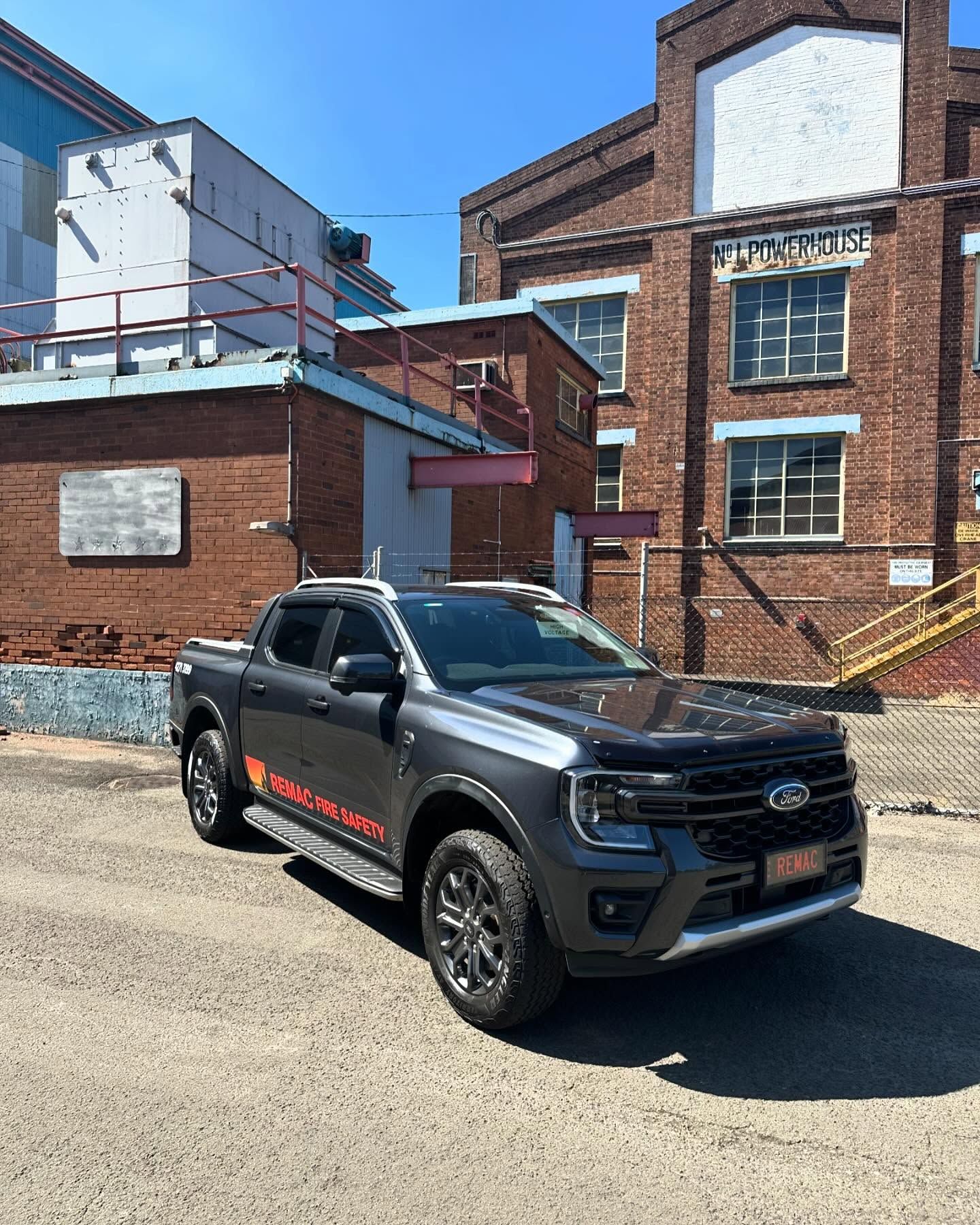 A black truck is parked in front of a brick building. A black truck is parked in front of a brick building.