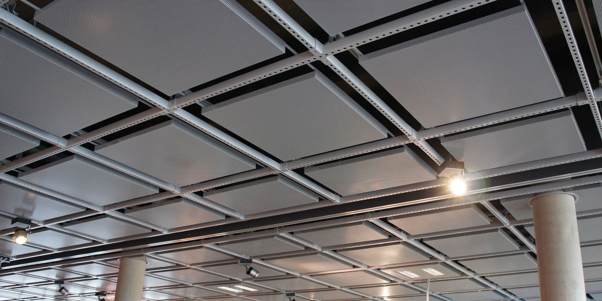 Metallic ceiling tiles with recessed lighting in a commercial space.