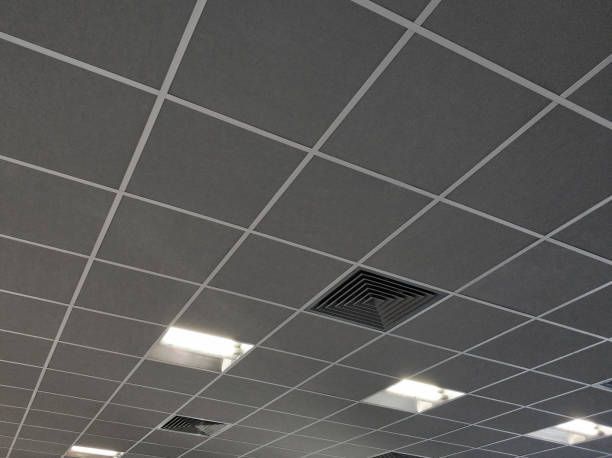 Gray tiled ceiling with white grid, recessed lights and a vent.