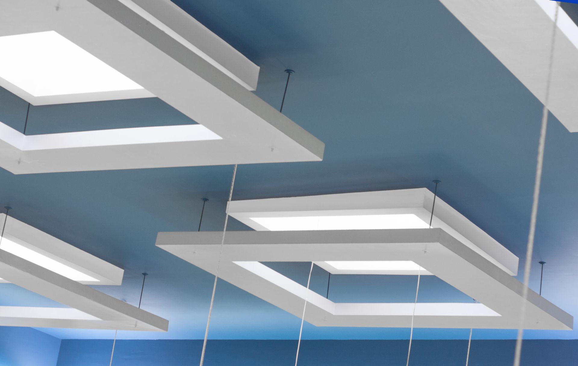 White suspended ceiling with a blue base and square lights. White square light fixtures suspended from a blue ceiling, creating a modern interior.