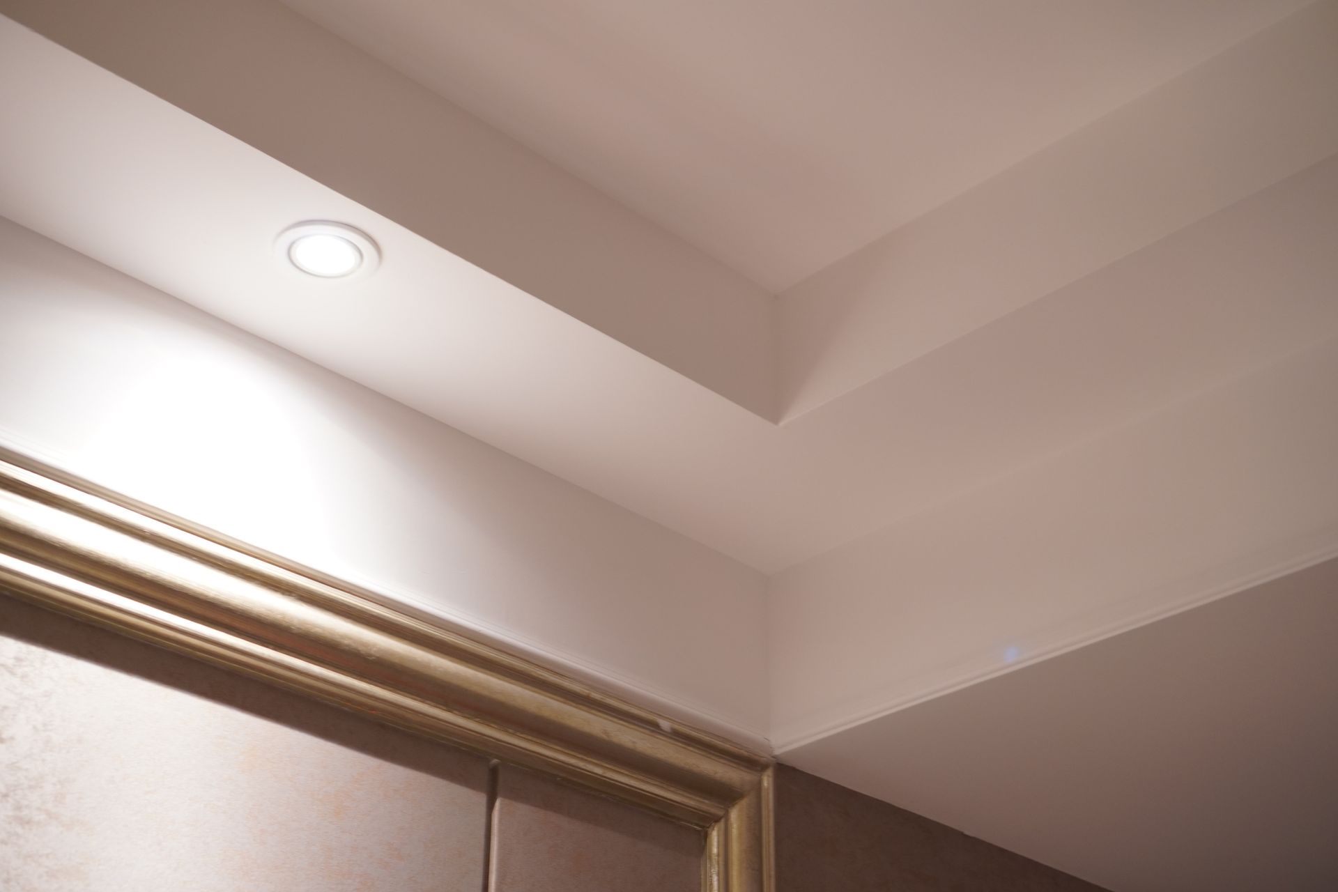 White ceiling with recessed light, and decorative molding around a door.