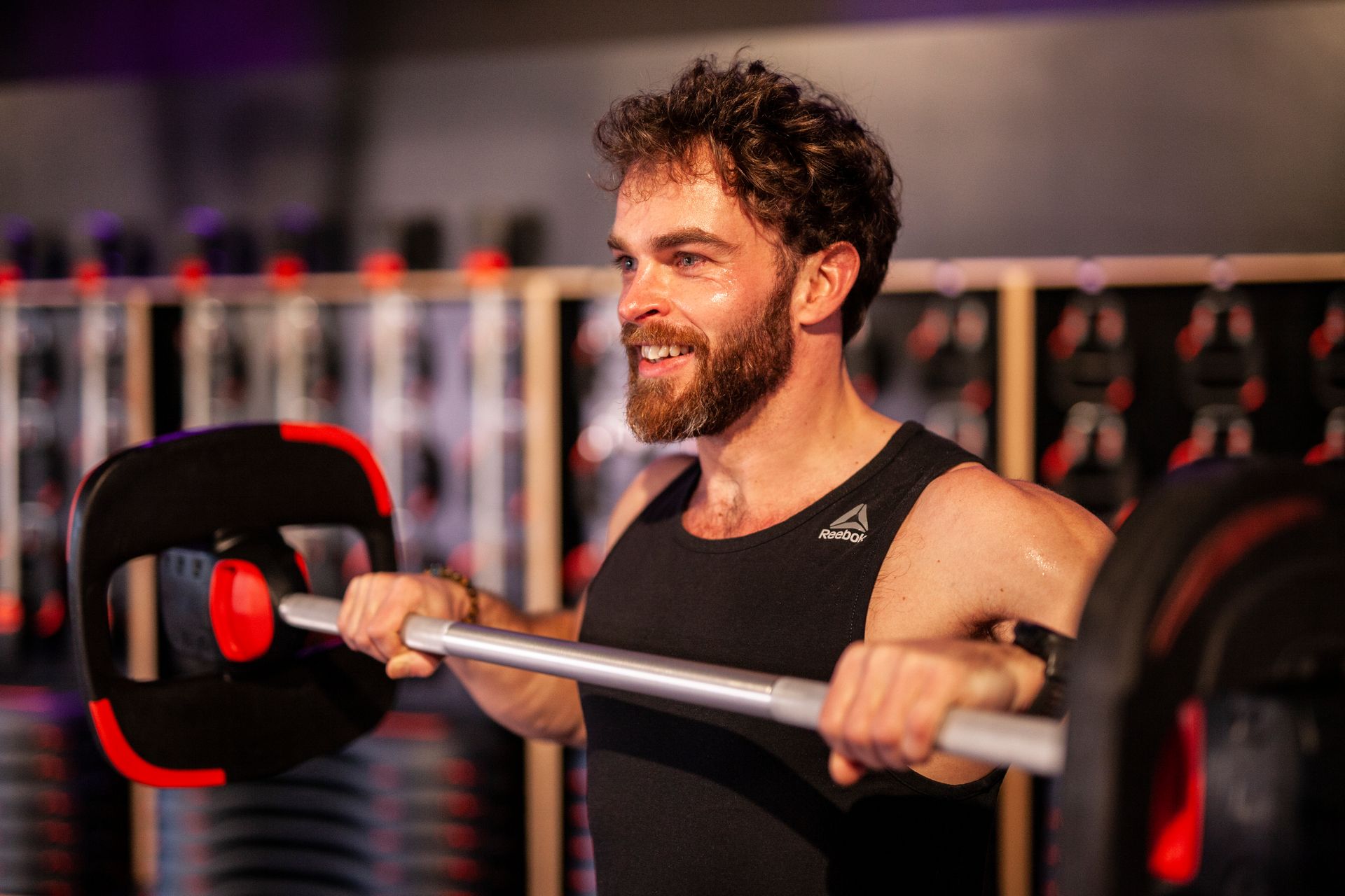 Een man tilt een halter op in een sportschool.
