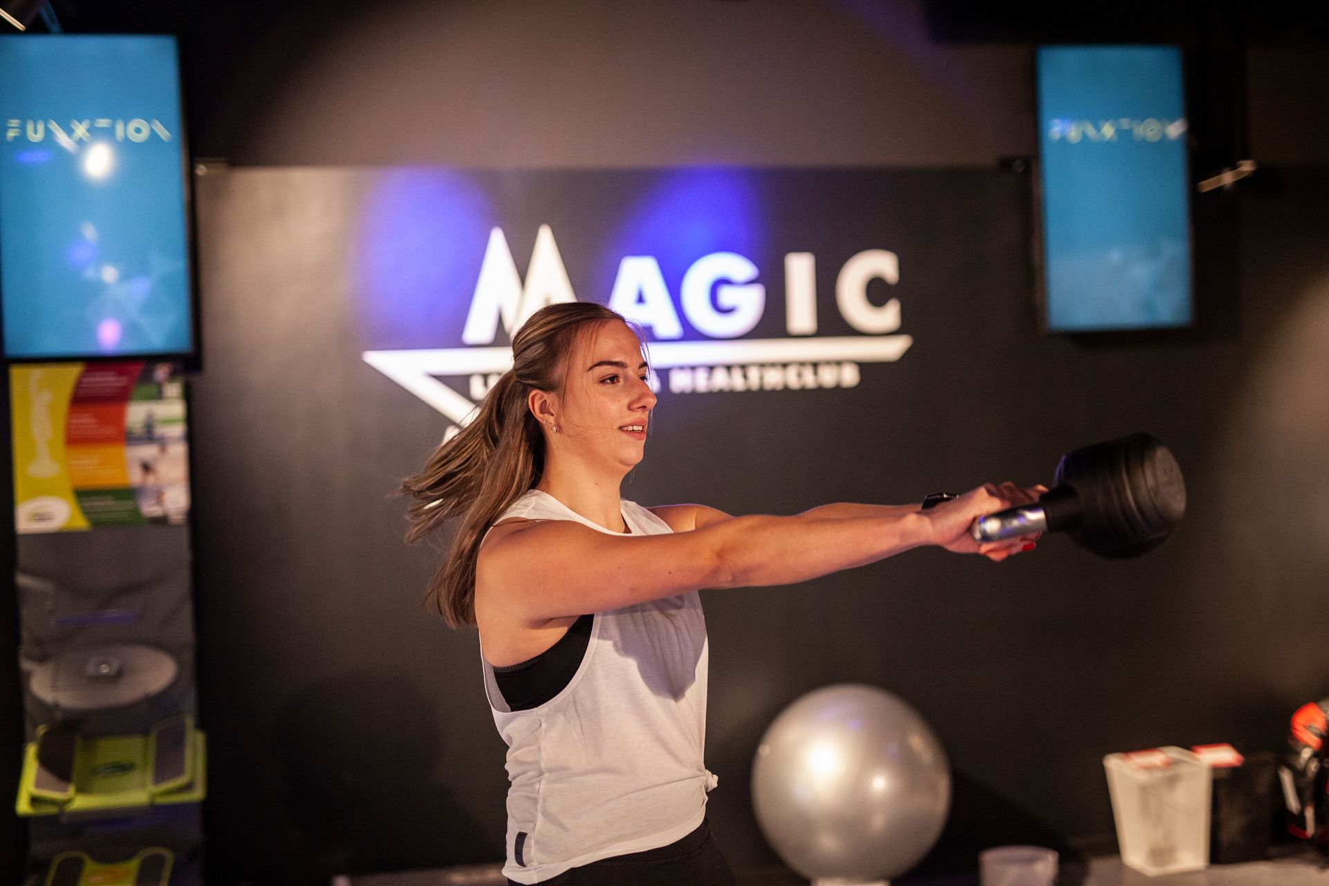 Een vrouw zwaait met een kettlebell in een sportschool.