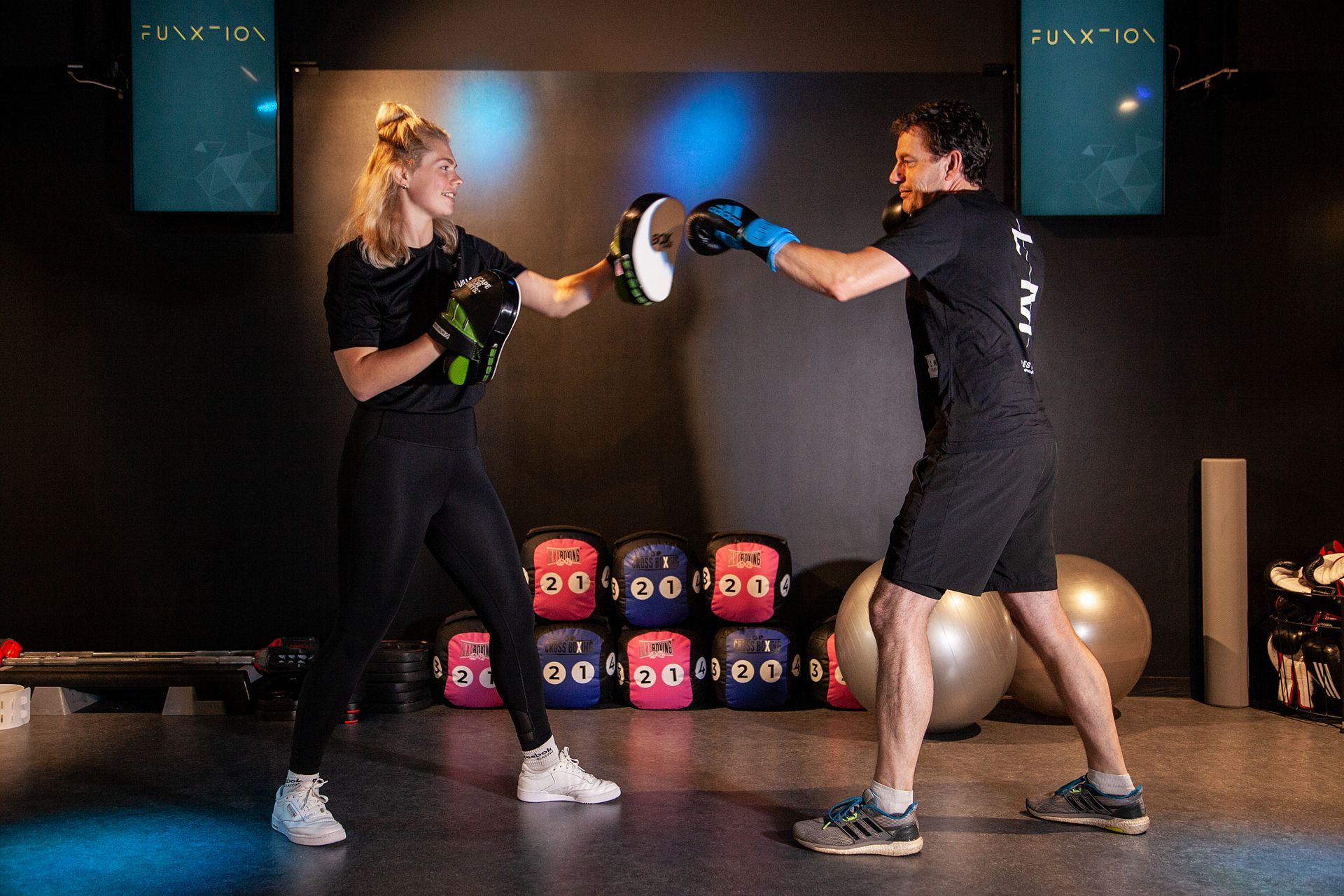 Een man en een vrouw zijn aan het boksen in een sportschool.