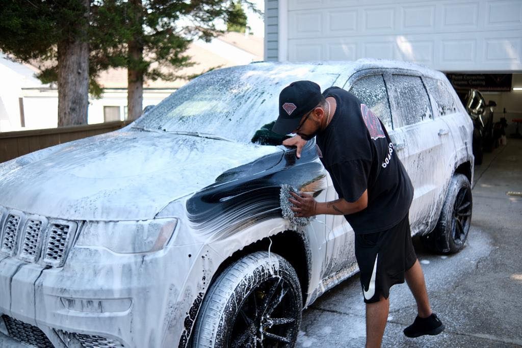 a man is washing a car with foam in a parking lot .