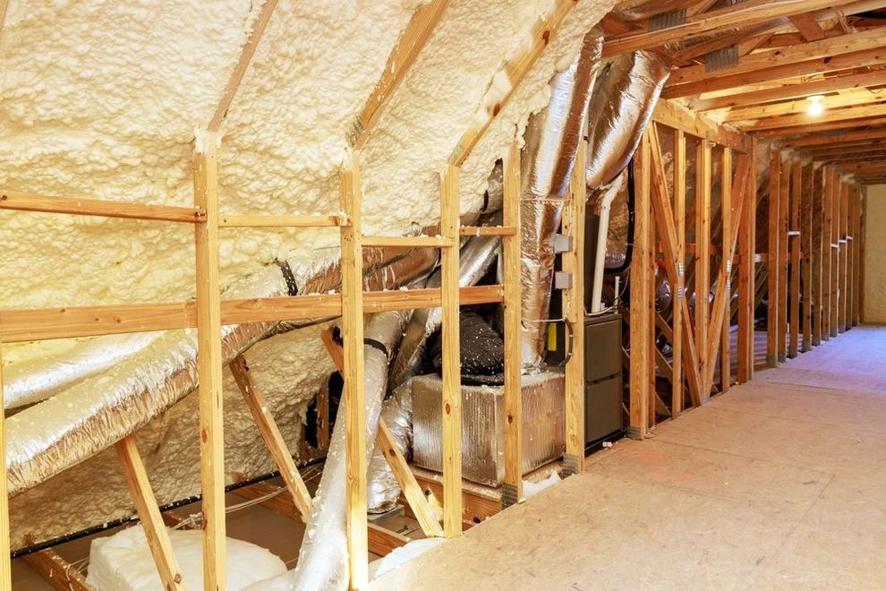 Insulated attic with exposed wooden framing and HVAC ductwork along the floor