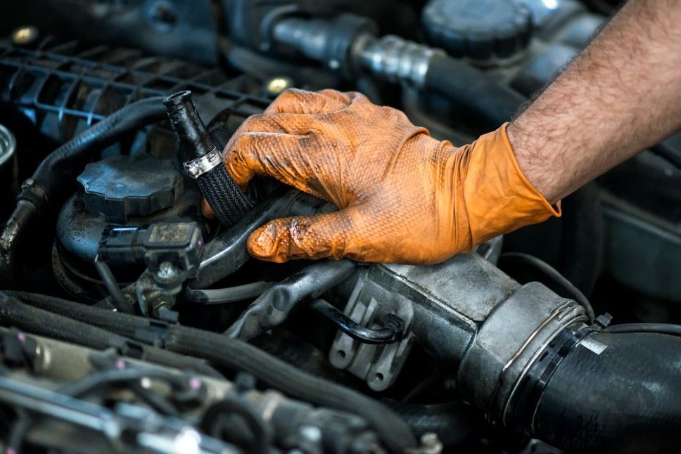 A Man Wearing Orange Gloves is Working on a Car Engine — Pialba Brake Clutch & Steering Centre in Pialba, QLD