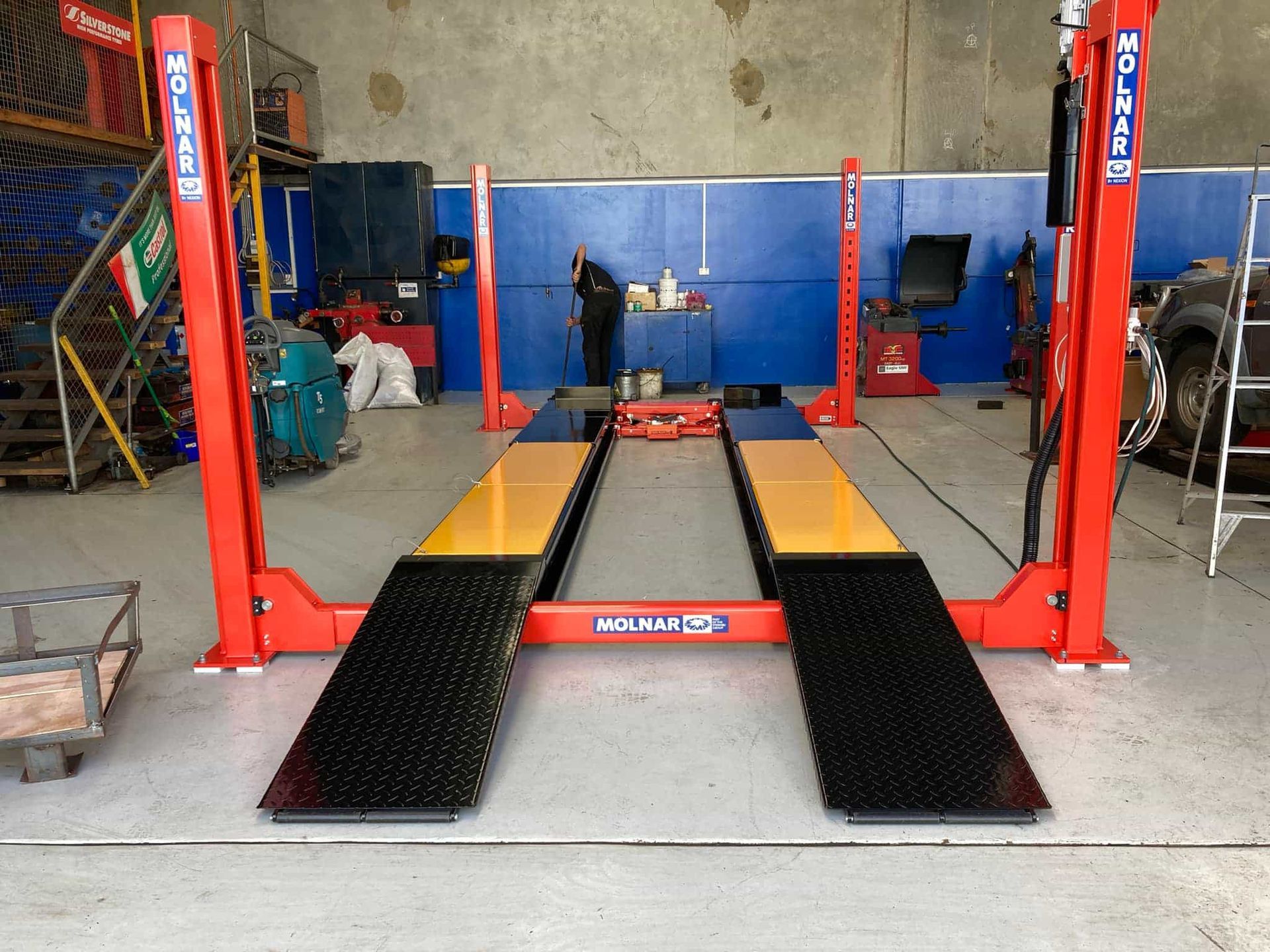 A red and yellow car lift in a garage — Pialba Brake Clutch & Steering Centre in Pialba, QLD