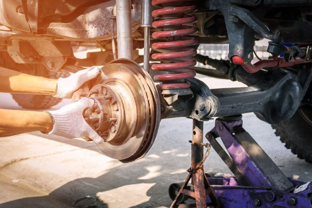 A Man is Working on the Brake Disc of a Truck — Pialba Brake Clutch & Steering Centre in Pialba, QLD