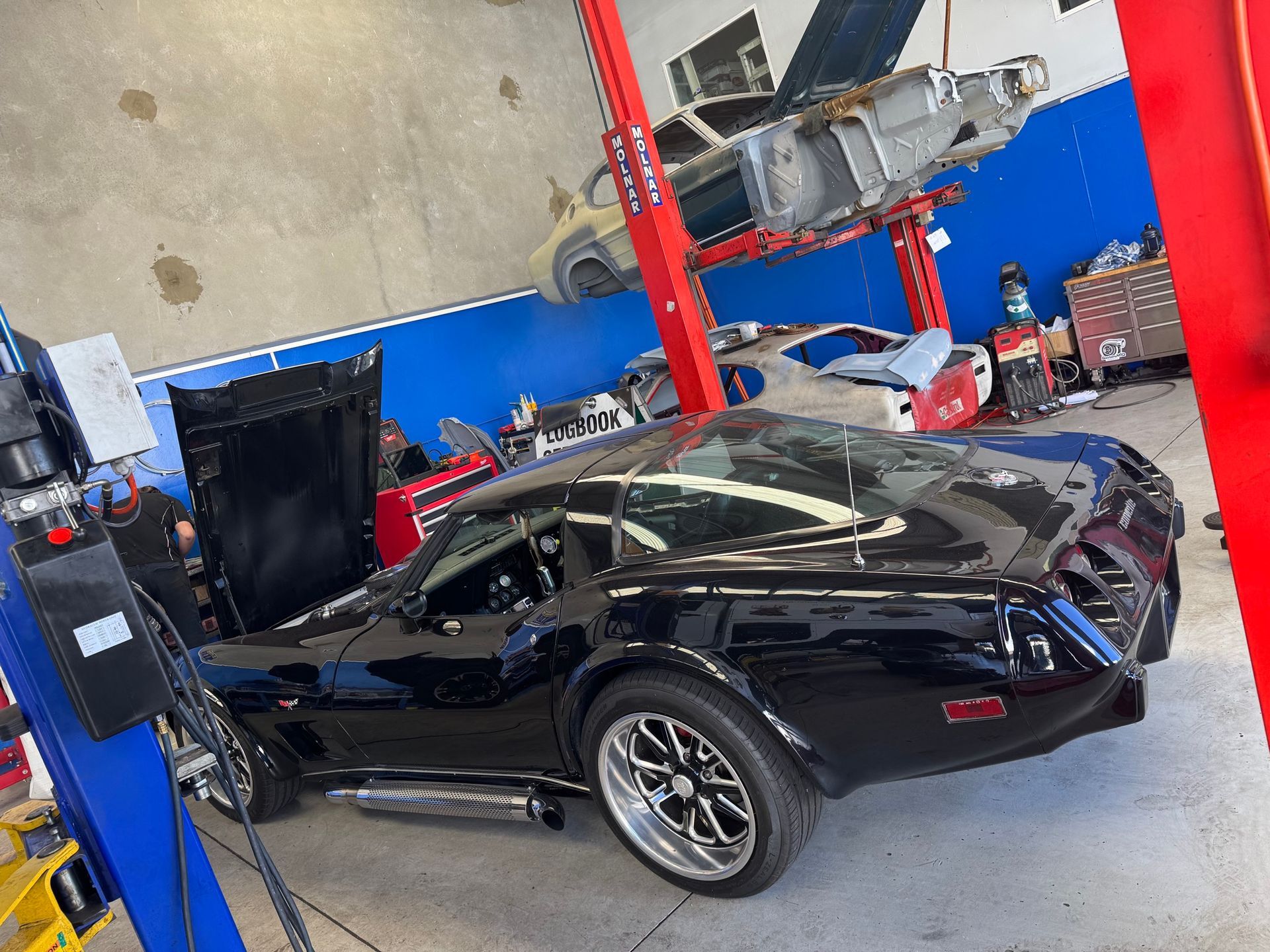 Two Cars Are Sitting on a Lift in a Garage — Pialba Brake Clutch & Steering Centre in Pialba, QLD
