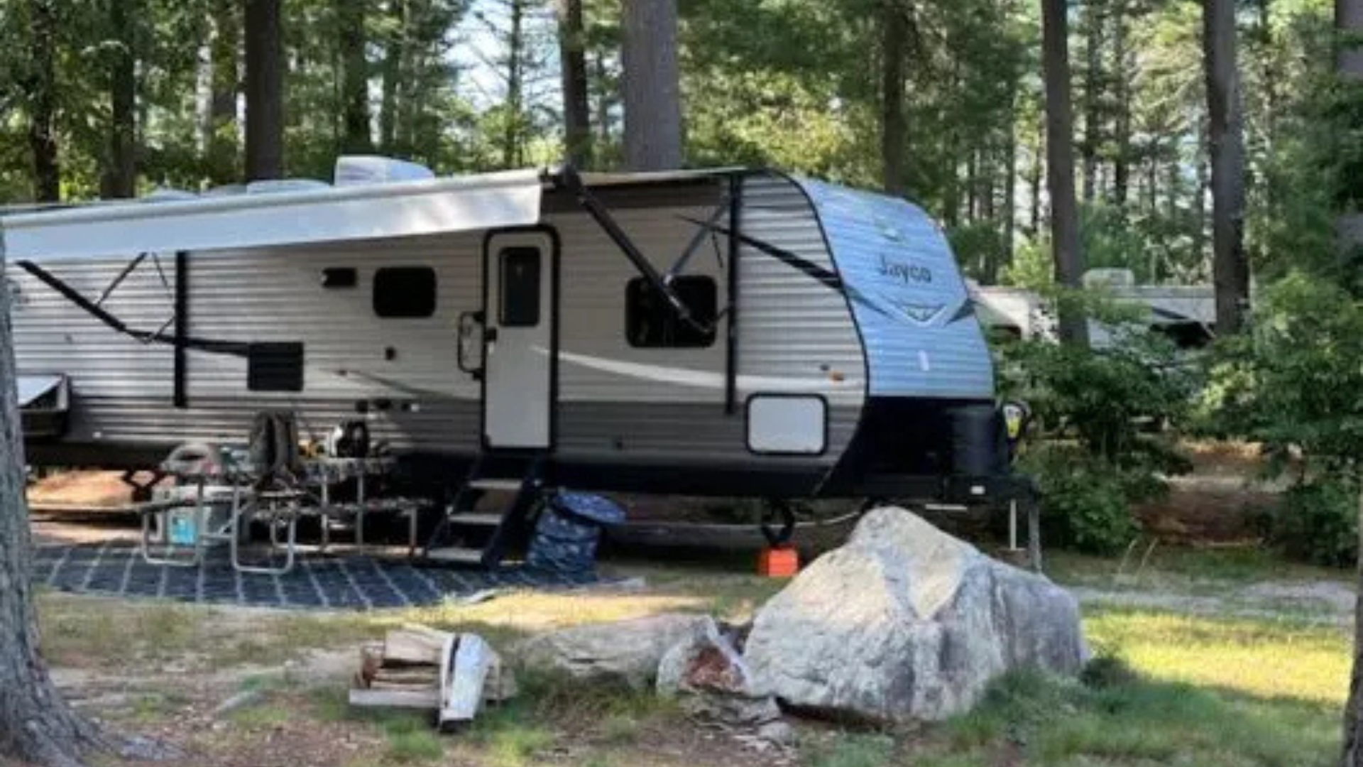 A rv is parked in a campground in the woods.