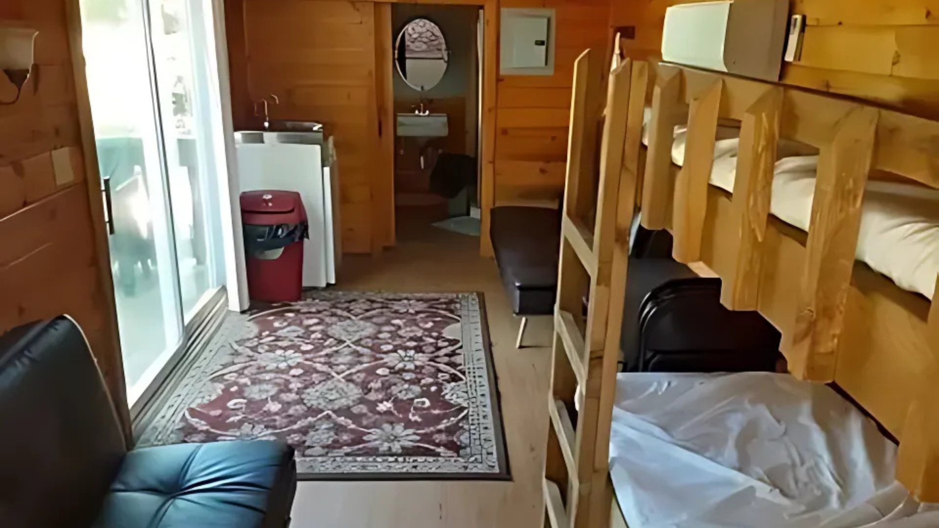 A room with bunk beds , a couch , and a rug.