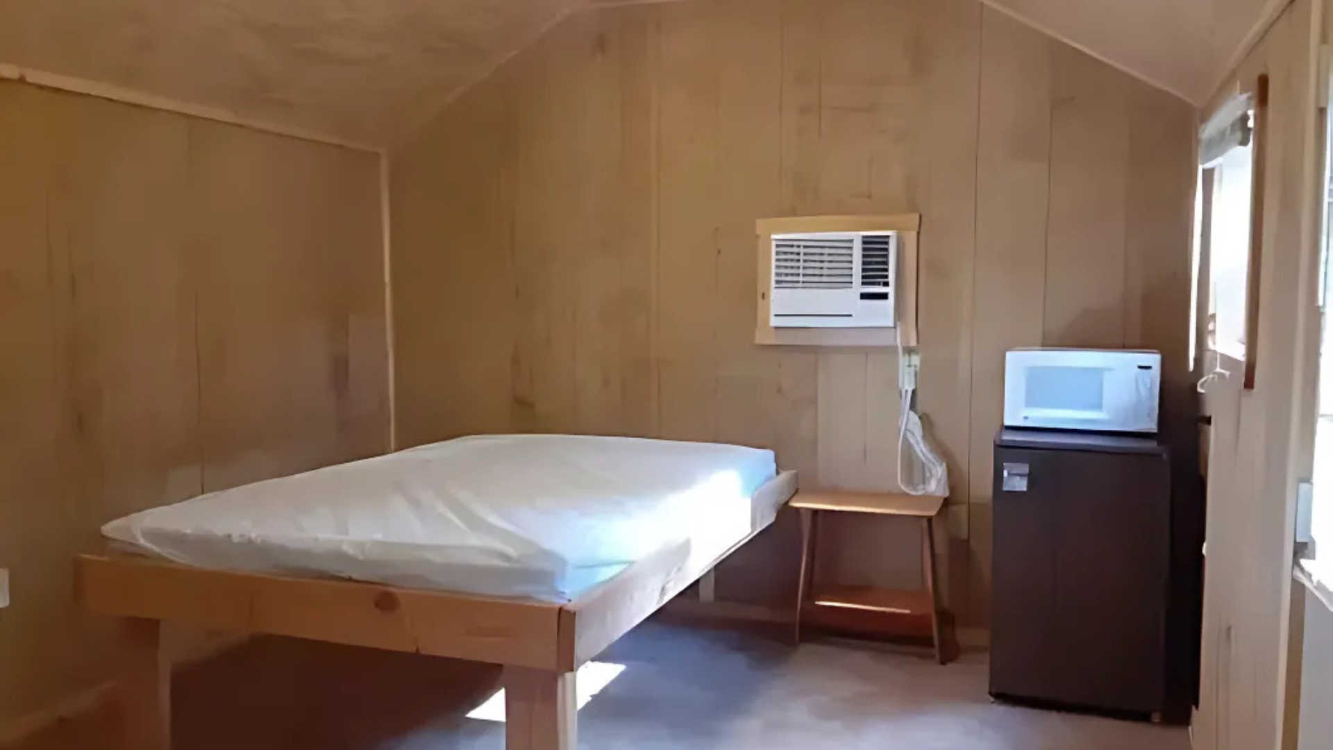 A bedroom with a bed , microwave , and refrigerator.