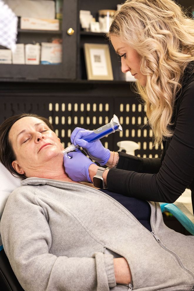 Caregiver administering a neck injection to a reclining patient in a clinical setting