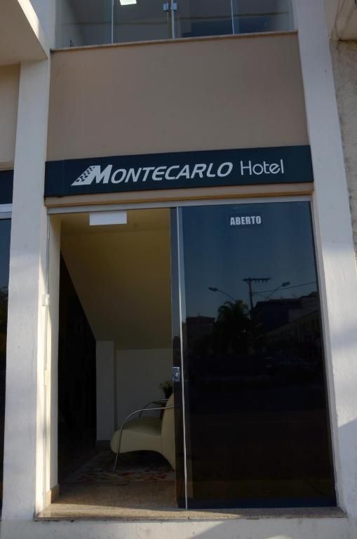Entrada do Hotel Montecarlo com portas de vidro e fachada bege.