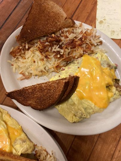 Plate with toast, shredded hash browns, and melted cheese on a wooden table.