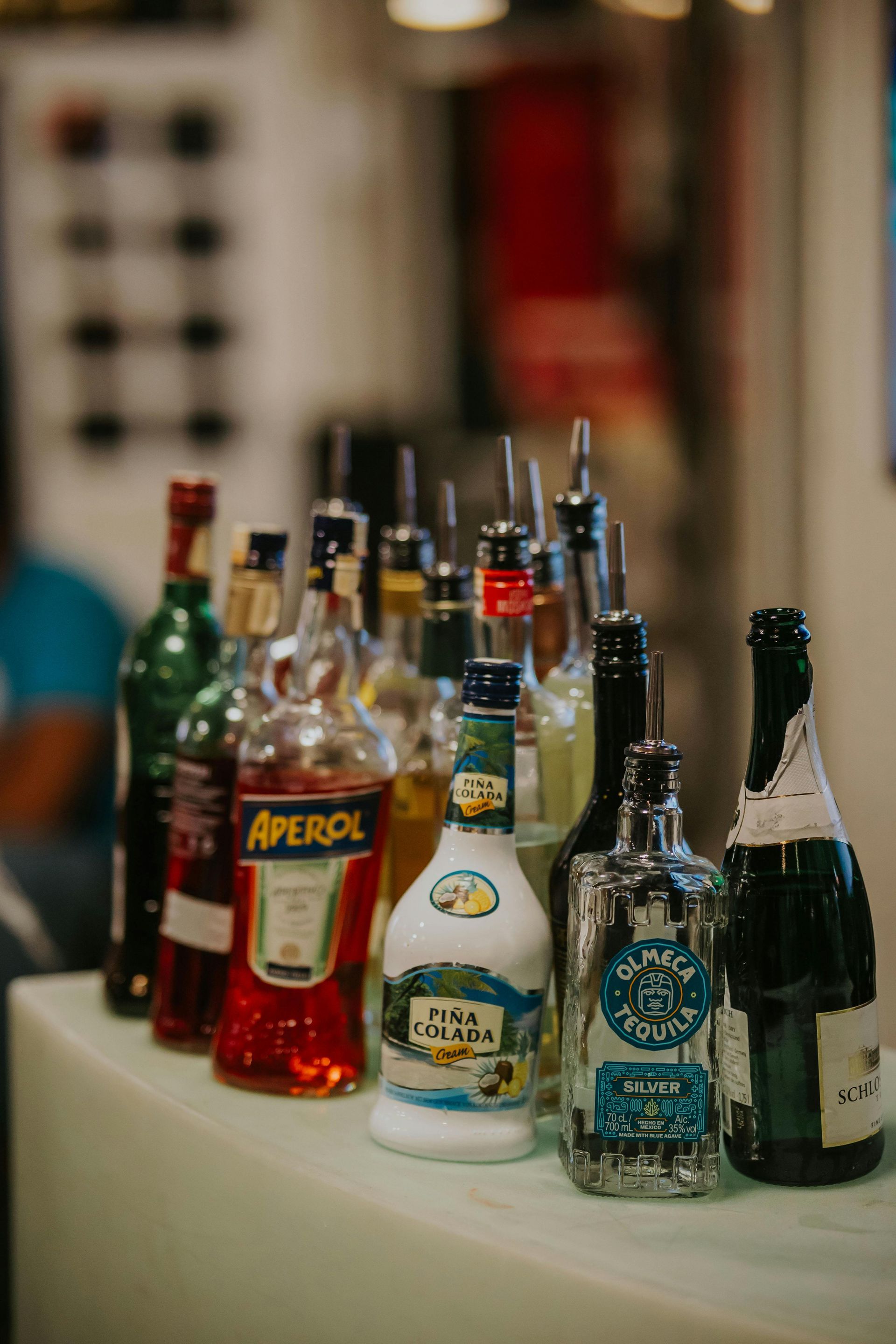 Assorted liquor bottles displayed on a table at a blurred indoor event.
