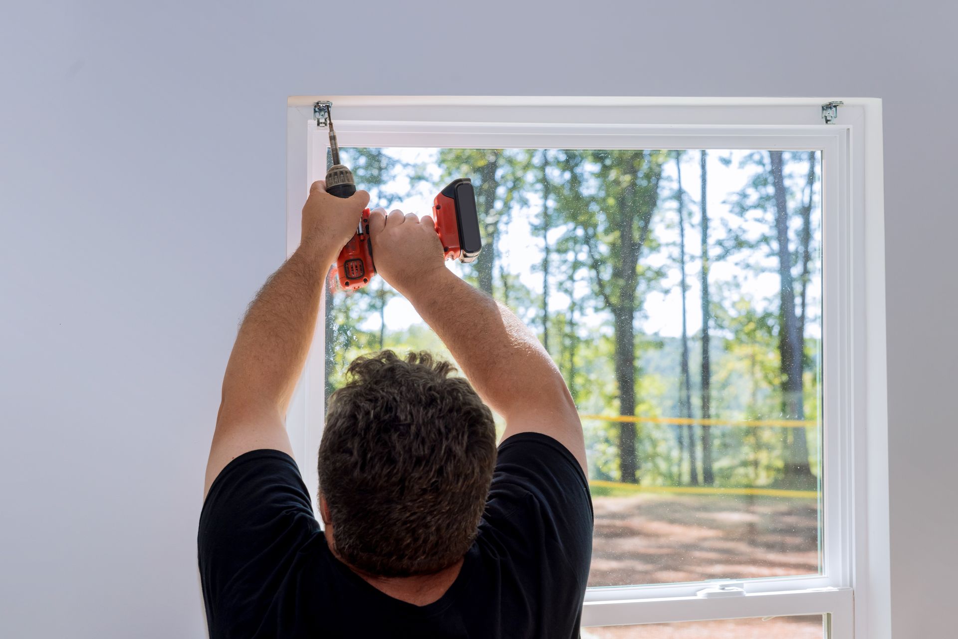 A man is installing a window with a drill.