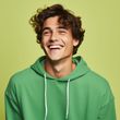 A young man wearing a green hoodie is smiling