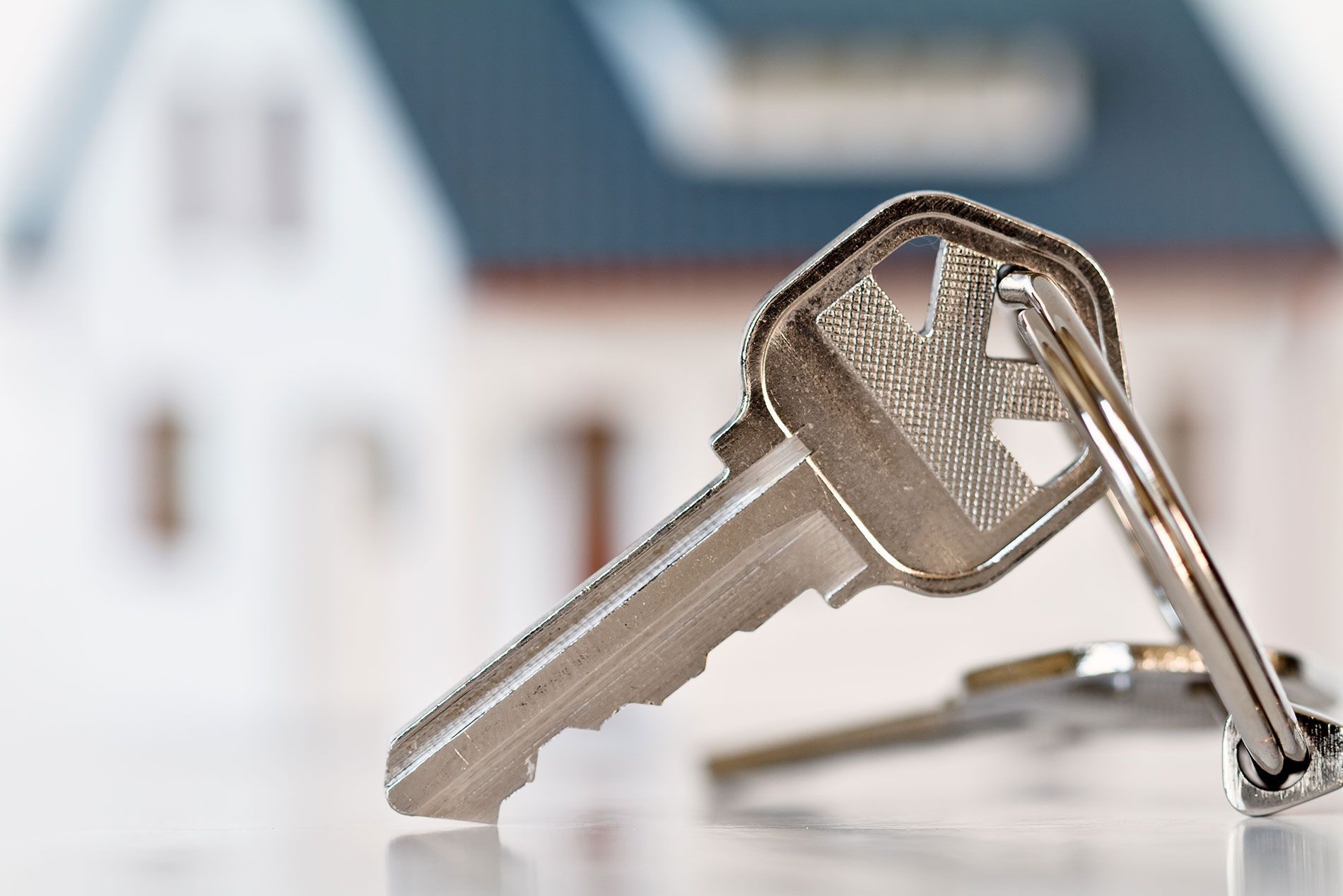 A Close up Of a Key with A House in The Background