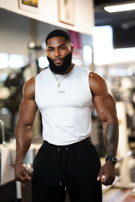 A man with a beard is wearing a black tank top