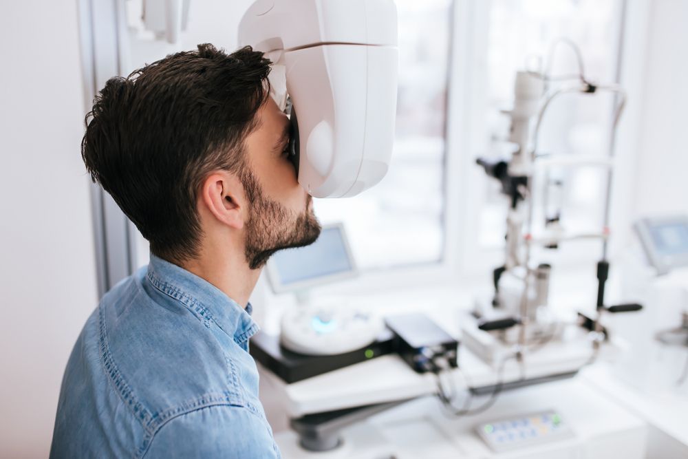 A Person With a Beard, Face Into an Ophthalmic Diagnostic Device — Peninsula Eyecare Izzards Optometrists in Gosford, NSW