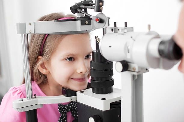 A Person Sitting at a Slit Lamp Microscope for an Eye Examination — Peninsula Eyecare Izzards Optometrists in Woy Woy, NSW