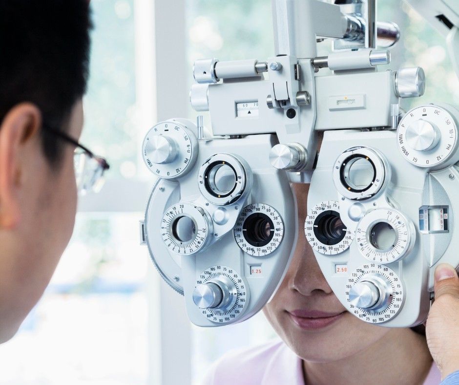 An Optometrist Performs an Eye Exam on a Patient Using a Phoropter — Peninsula Eyecare Izzards Optometrists in Woy Woy, NSW