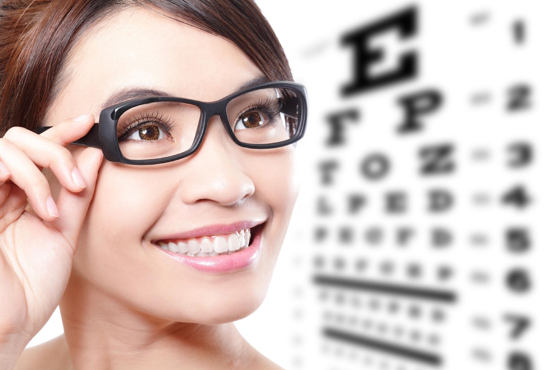 A Person Wearing Glasses in Front of a Blurred Eye Chart — Peninsula Eyecare Izzards Optometrists in Koolewong, NSW