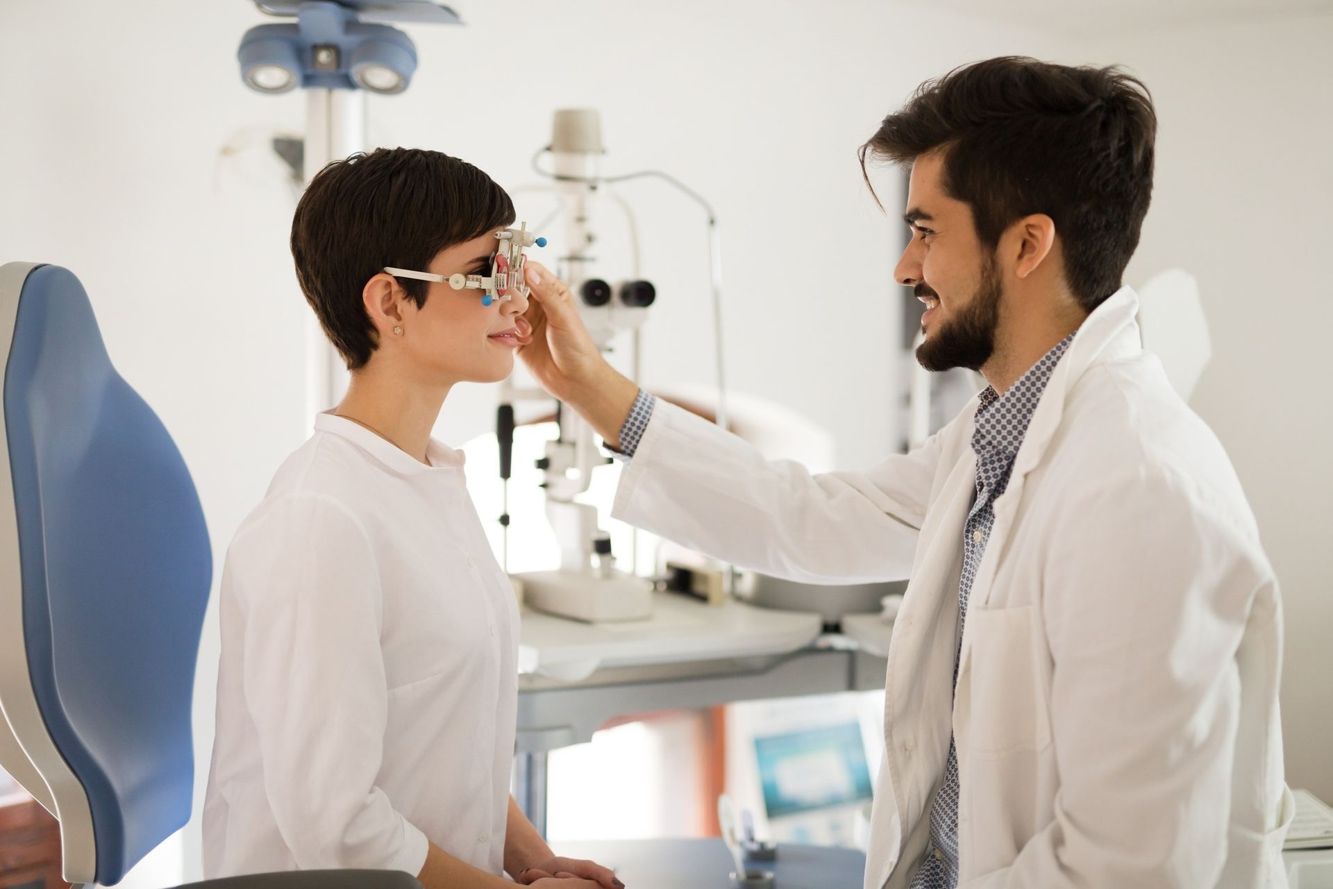 An Eye Doctor in a White Coat Adjusts Trial Frames — Peninsula Eyecare Izzards Optometrists in Woy Woy, NSW