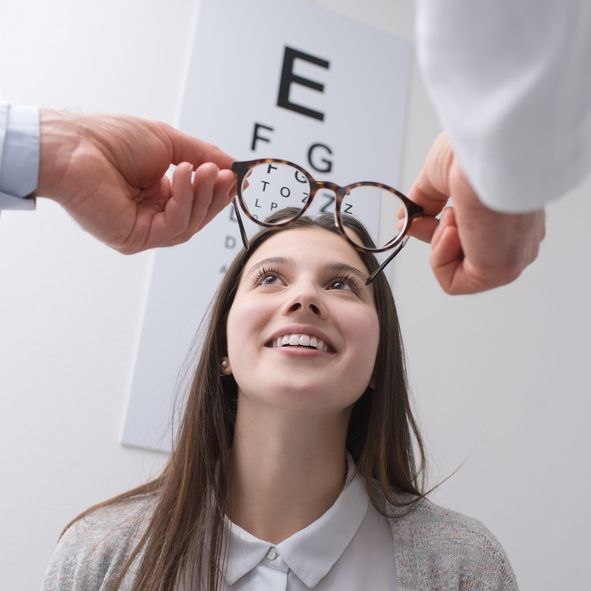 An Optometrist Holds Glasses in Front of a Patient — Peninsula Eyecare Izzards Optometrists in Woy Woy, NSW