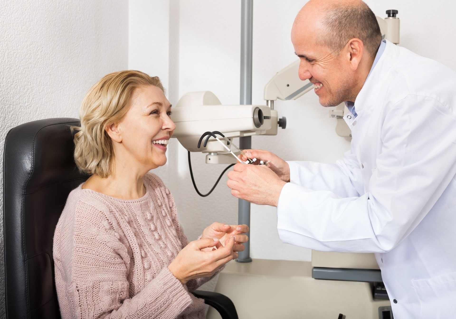 An Eye Doctor Adjusts Equipment for a Patient Seated in a Chair — Peninsula Eyecare Izzards Optometrists in Woy Woy, NSW