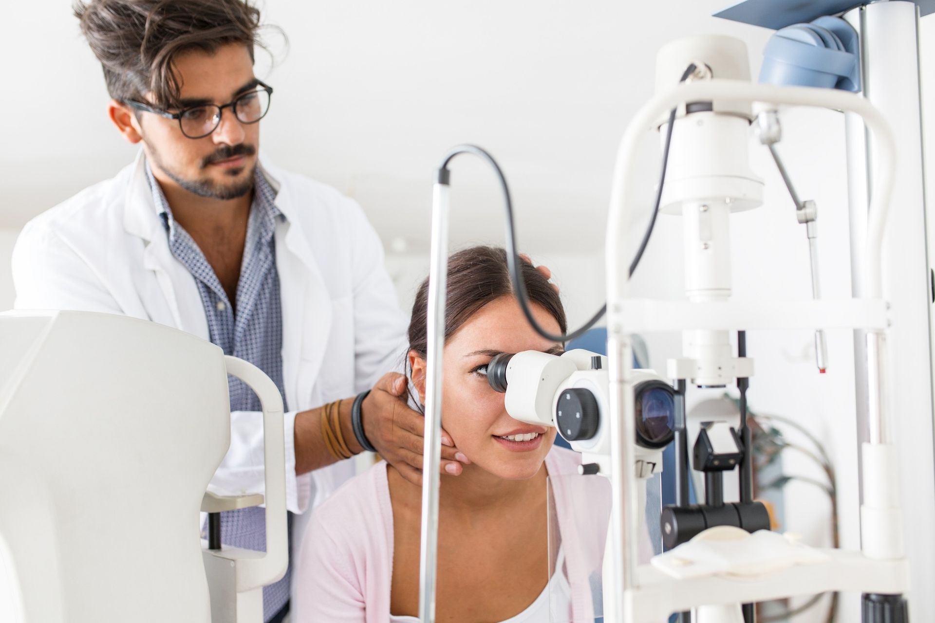 A Healthcare Professional in a White Coat Uses a Slit Lamp — Peninsula Eyecare Izzards Optometrists in Woy Woy, NSW 