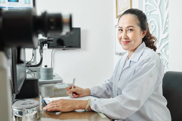 A Medical Professional in a White Coat Sits at a Desk — Peninsula Eyecare Izzards Optometrists in Woy Woy, NSW