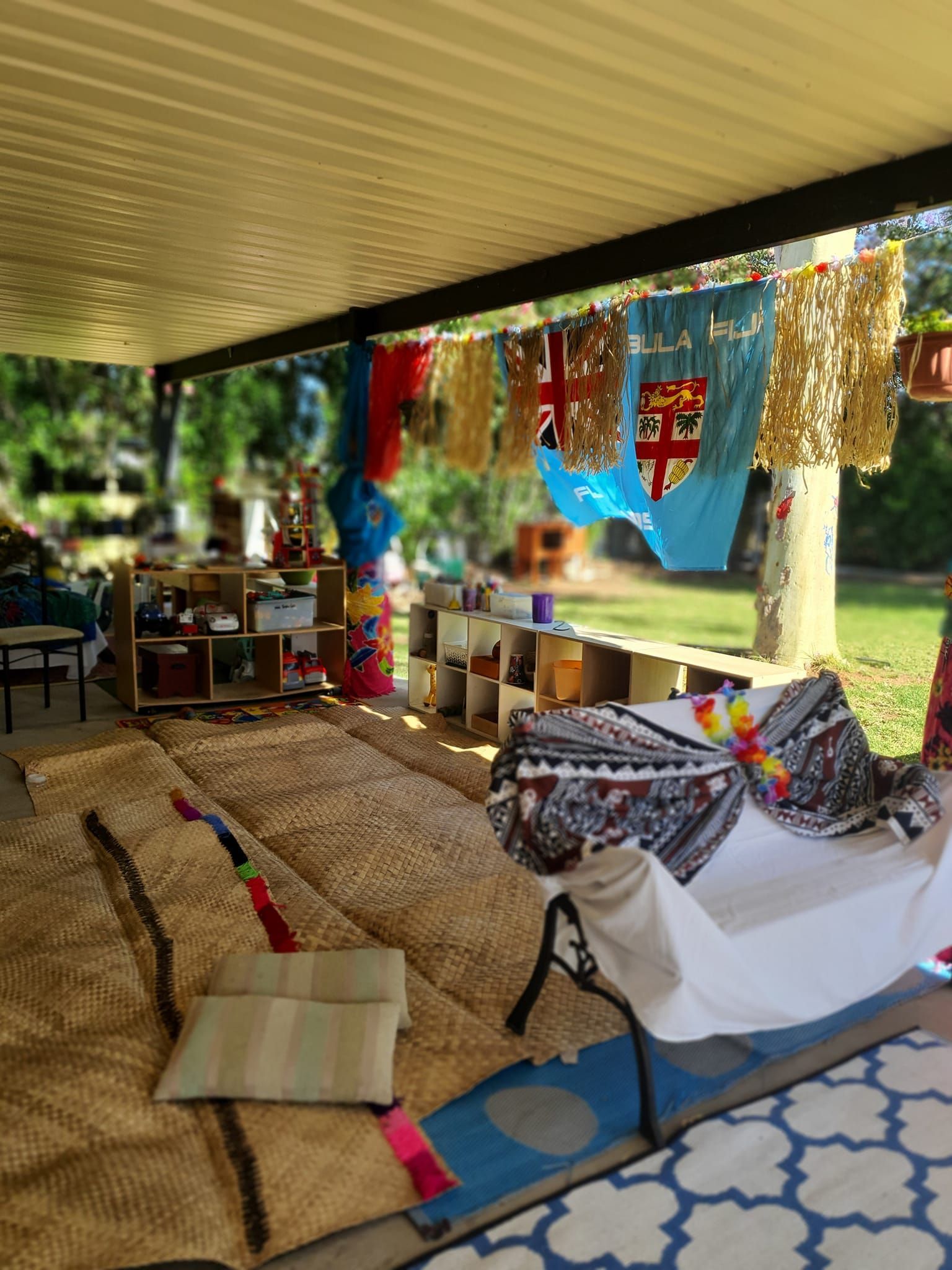 Outdoor classroom decorated with Fiji flags, rugs, and seating.