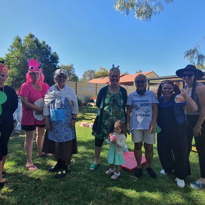 Group of people in costumes pose outside on a sunny day.