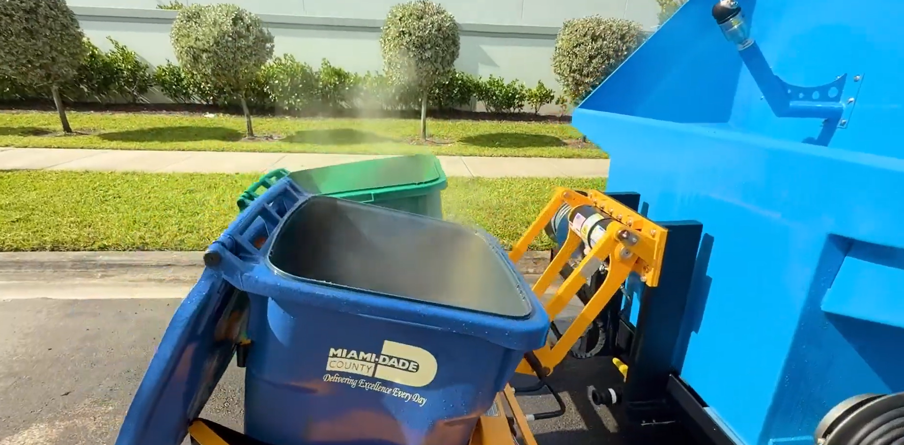 A person is holding a spray bottle over a trash can.