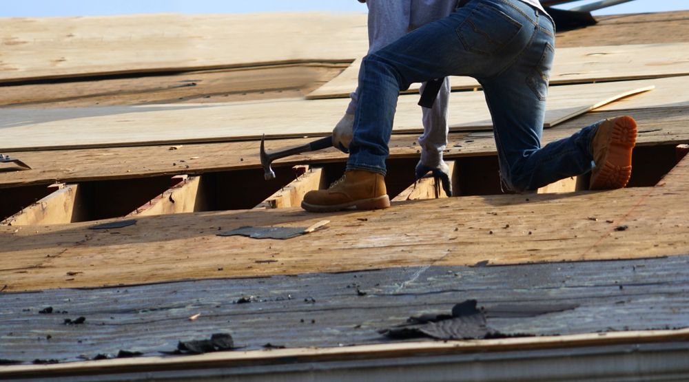 A Worker on a Roof Removes Damaged Decking With a Pry Bar — Wilko Plate (Aust) Pty Ltd in Innisfail, QLD