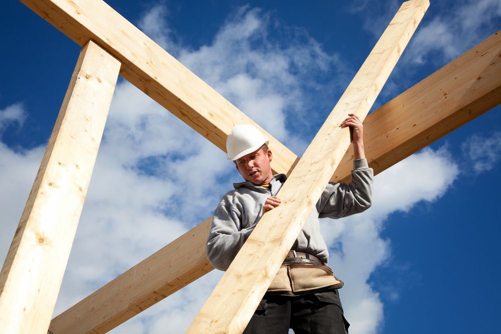 A Person Carrying a Wood for Roofing — Wilko Plate (Aust) Pty Ltd in Cairns, QLD