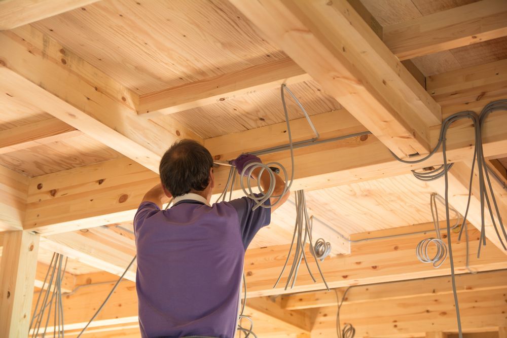Man in Purple Shirt Wiring Electrical Cables on a Wooden Ceiling — Wilko Plate (Aust) Pty Ltd in Mackay, QLD