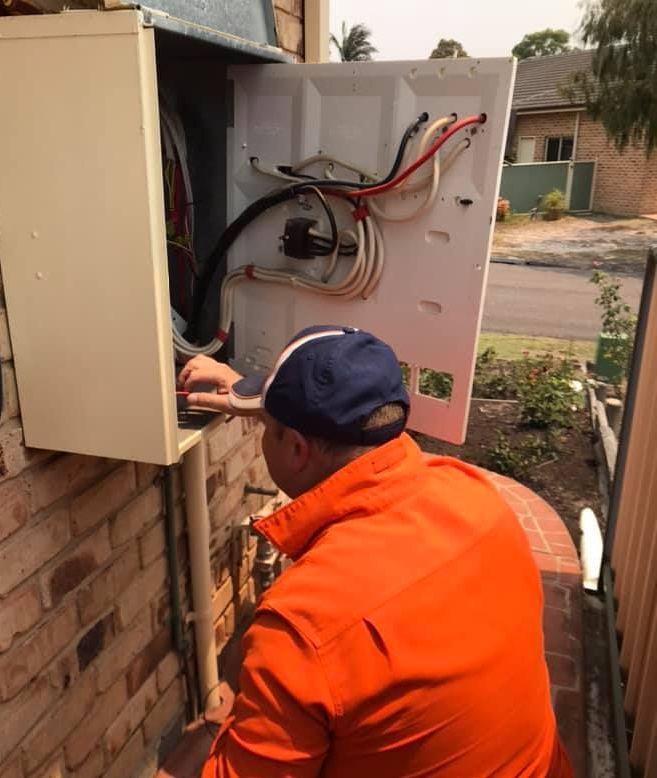 A Person is fixing a power switch or a main breaker outside a house — Gunter Electrical In Kariong, NSW