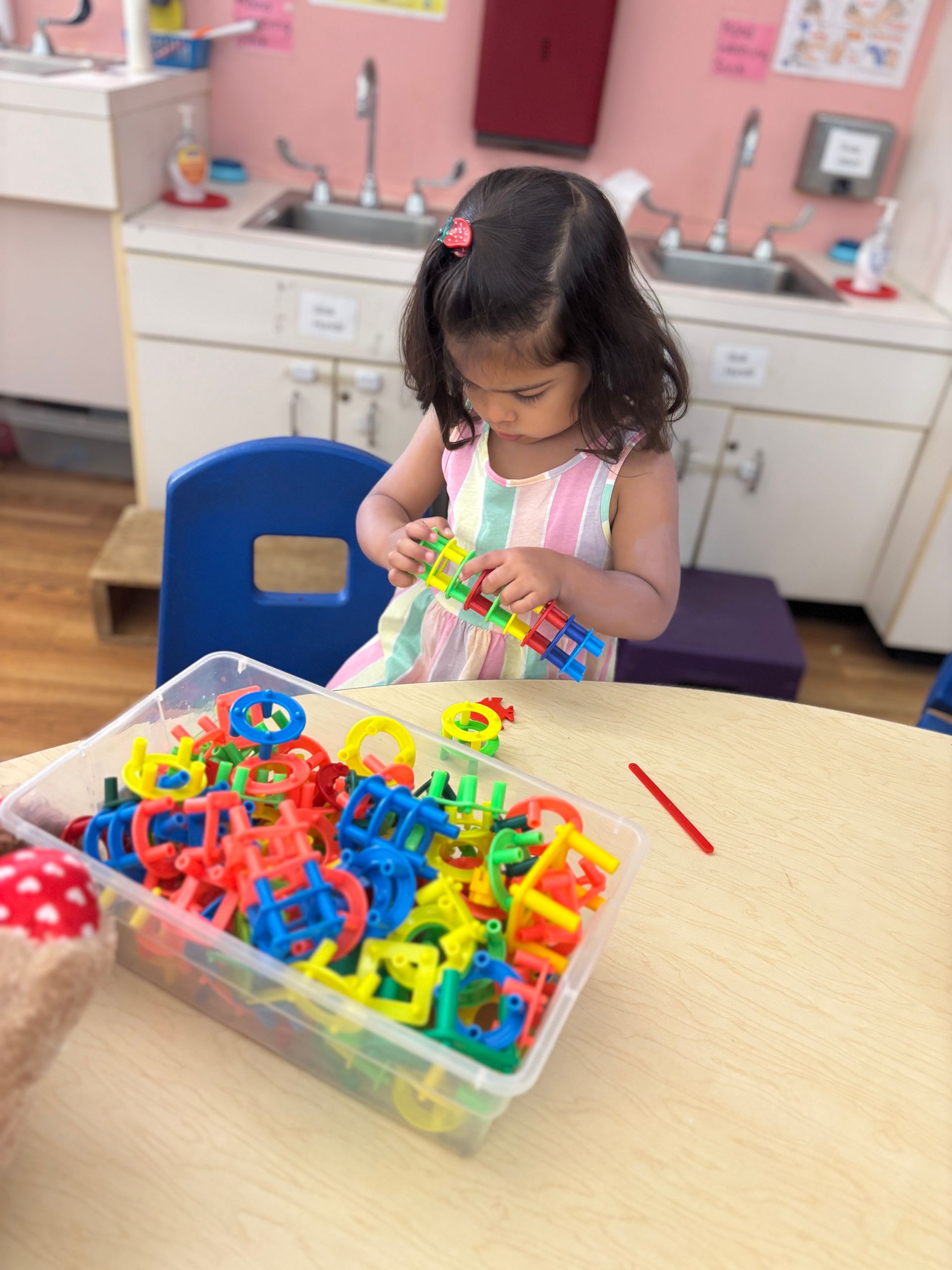 Smiling child holding a decorated Easter egg at a classroom table