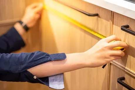A man is measuring a cabinet with a tape measure — Designer Kitchens in Berrimah, NT